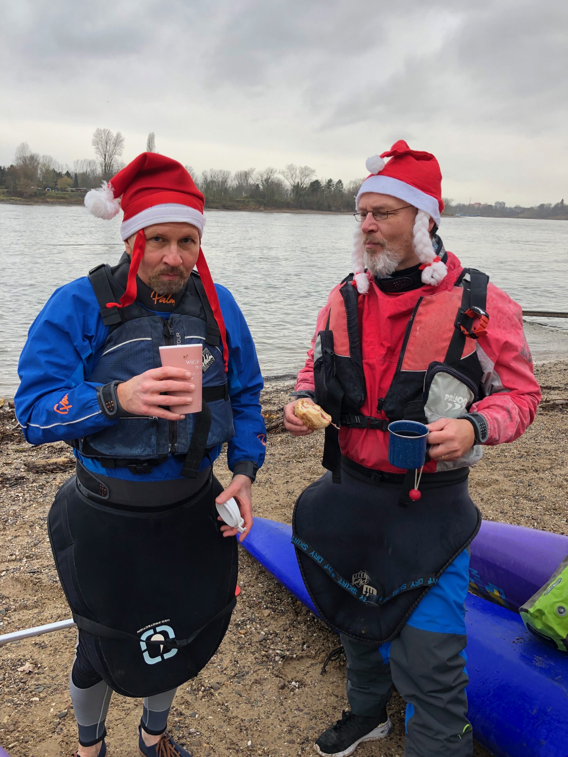 Zwei Kanufahrer mit Nikolausmützen und Glühwein in der Hand