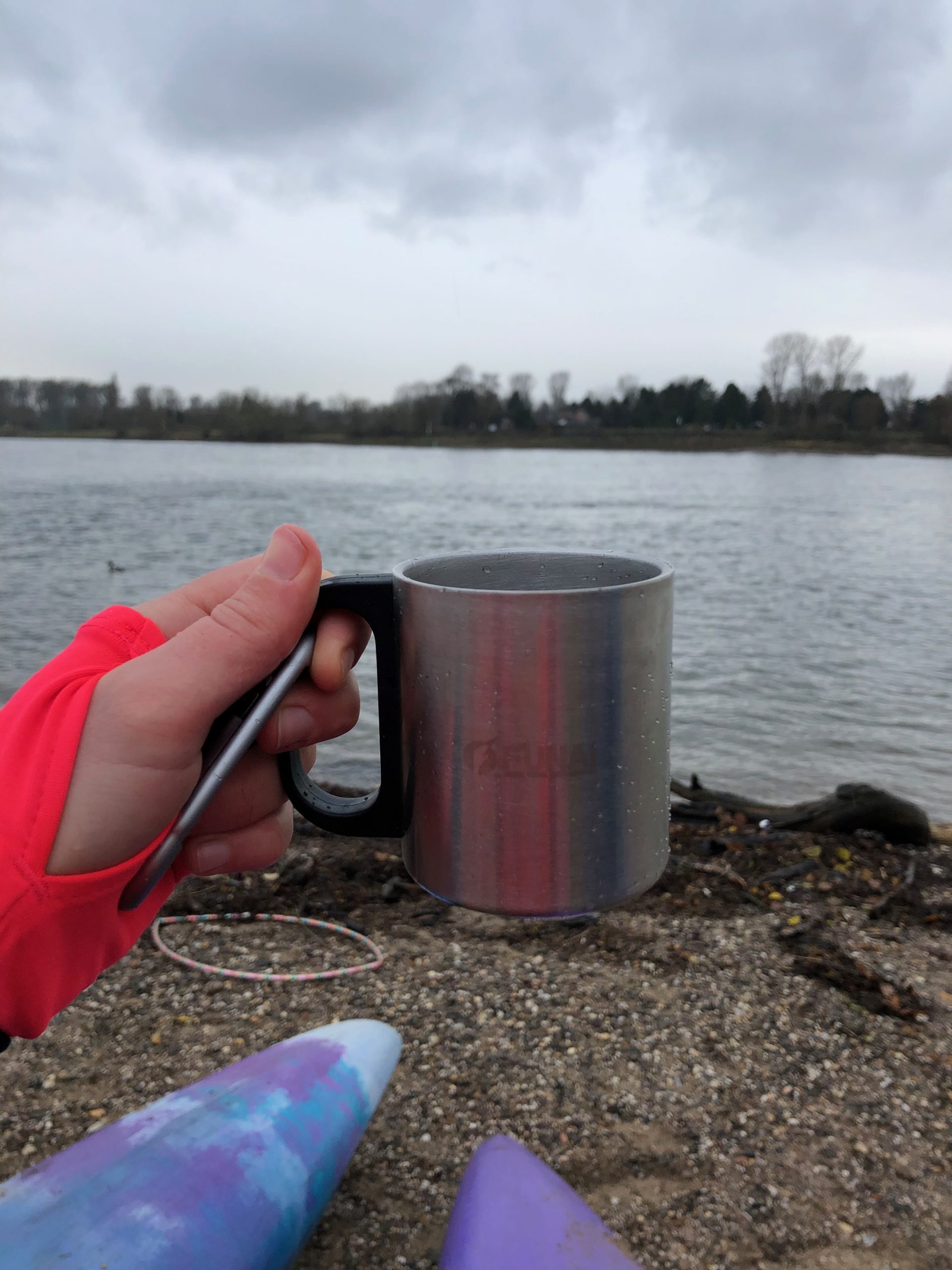 Metallbecher mit Glühwein vor dem Rhein