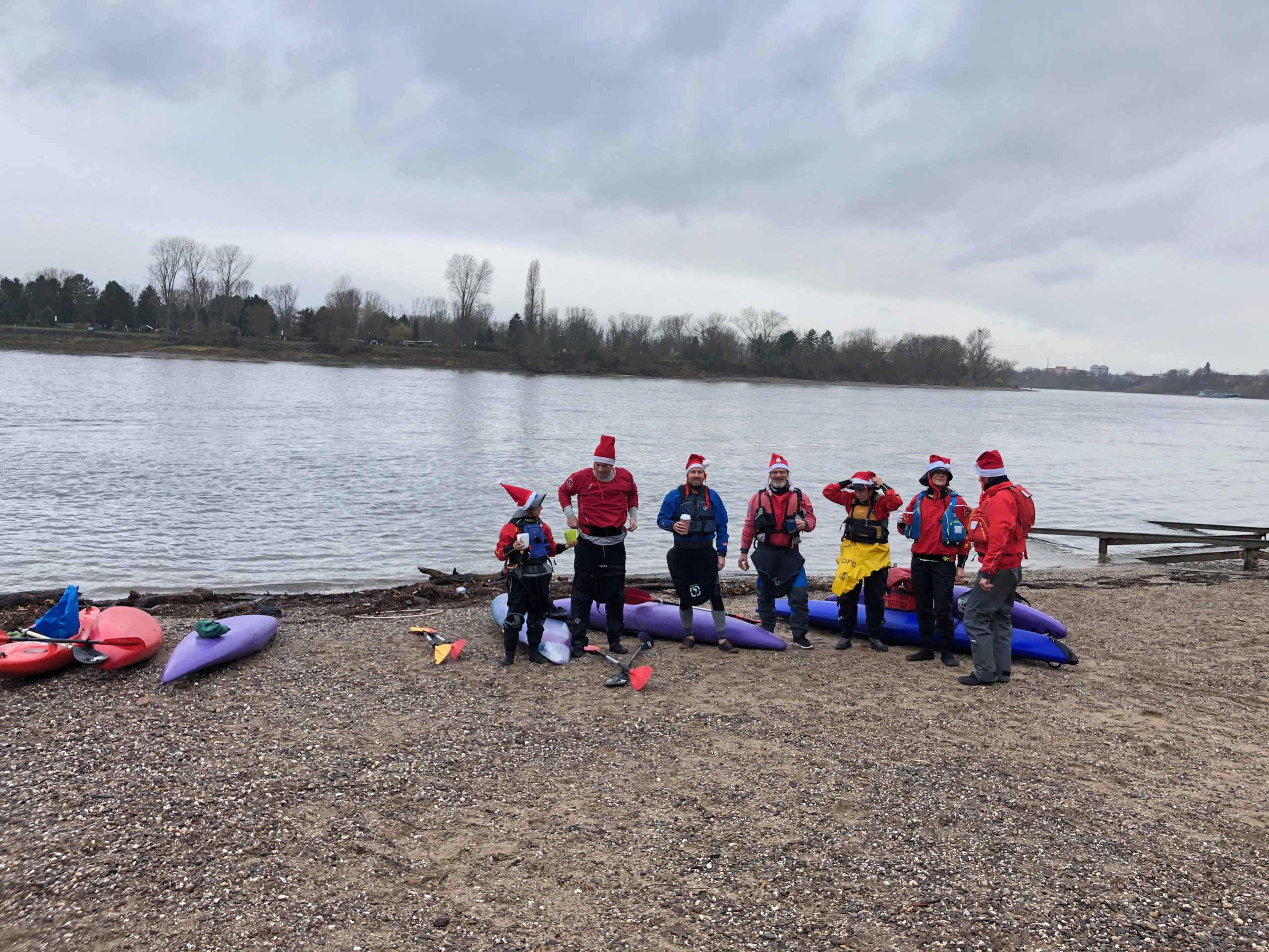 Gruppenfoto Kanufahrer mit Glühwein und Nikolausmützen am Rheinufer