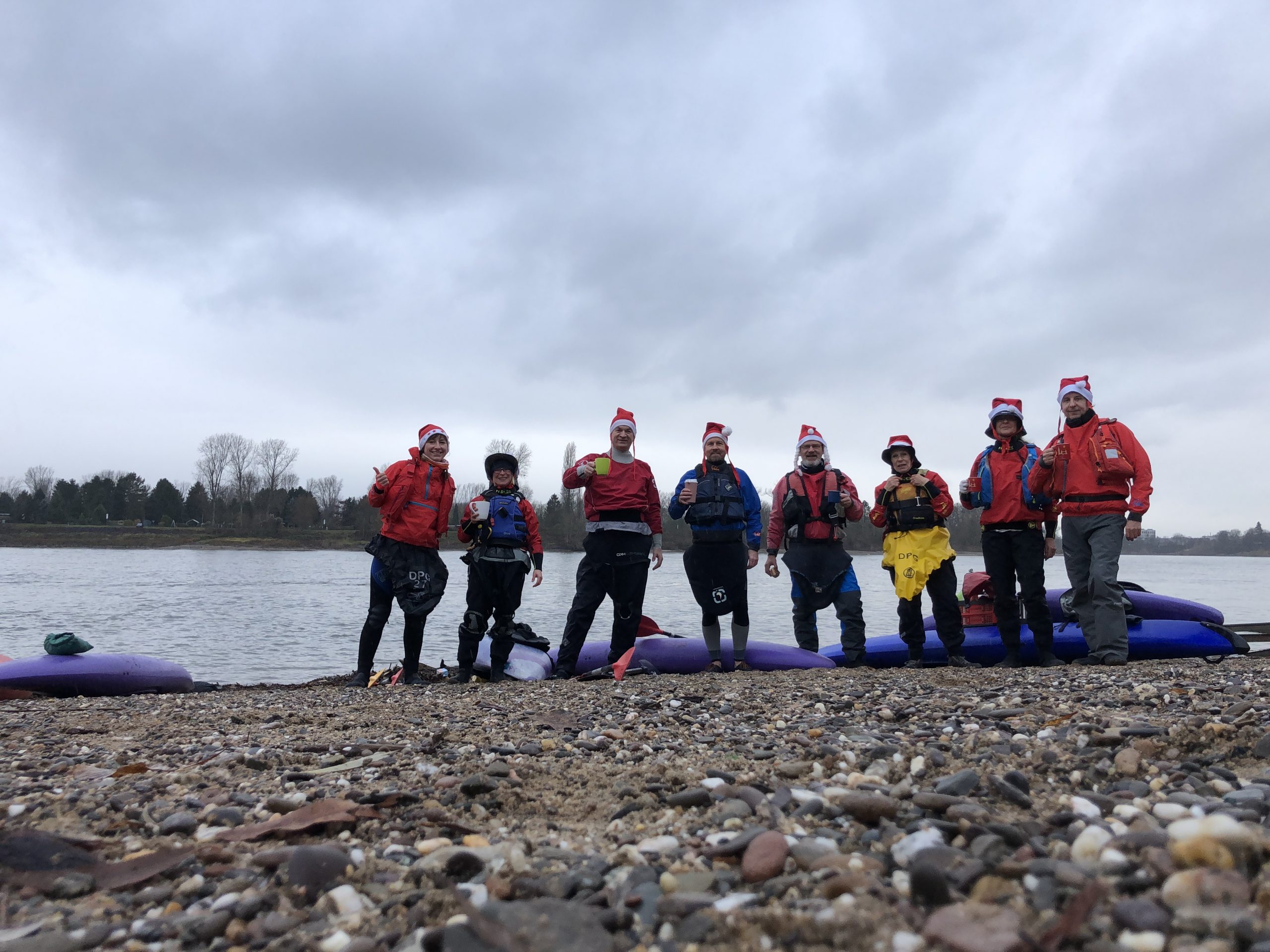 Gruppenfoto Kanufahrer mit Nikolausmützen am Rheinufer