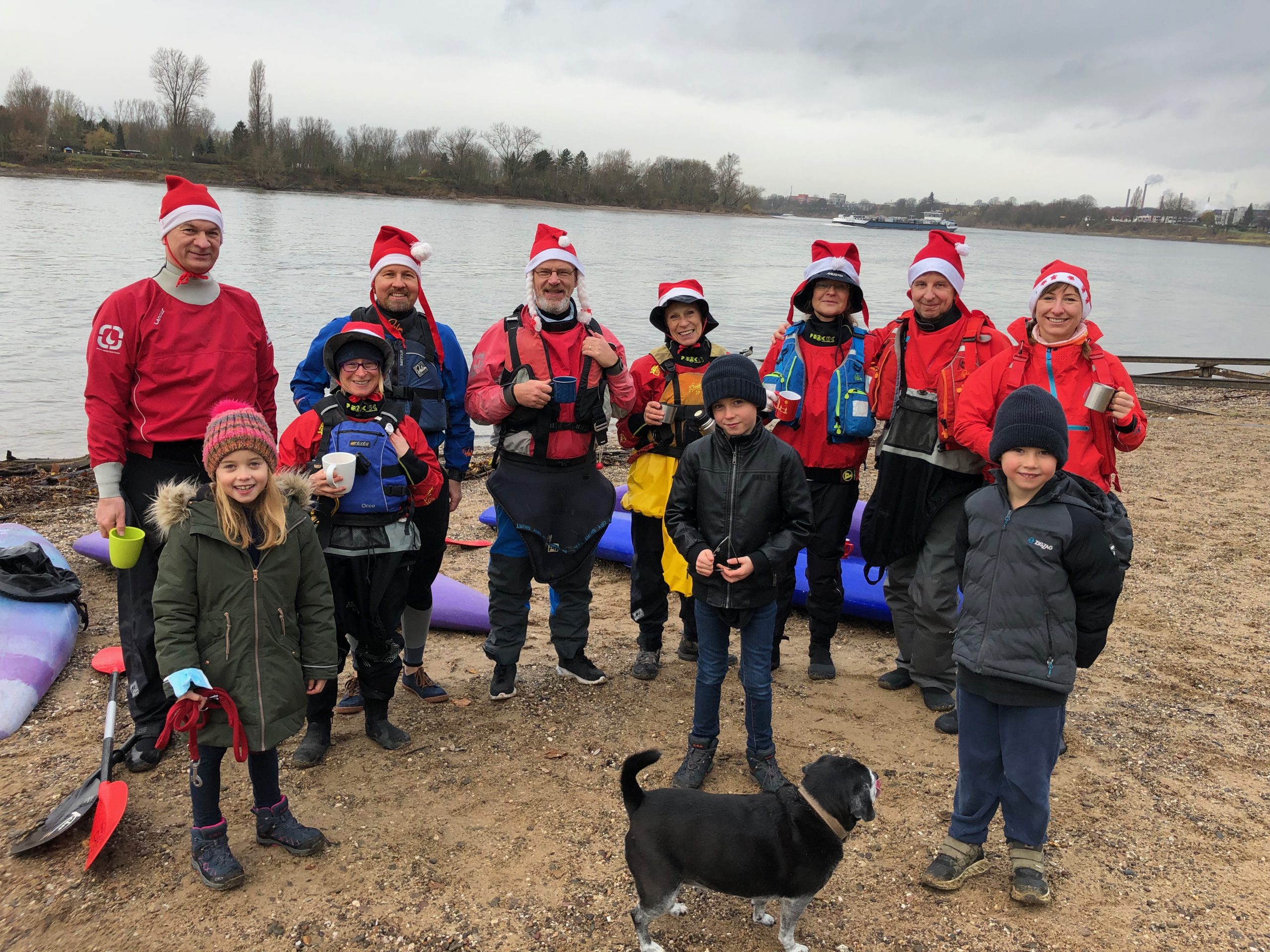 Gruppenfoto Kanufahrer mit Nikolausmützen am Rheinufer mit Kindern