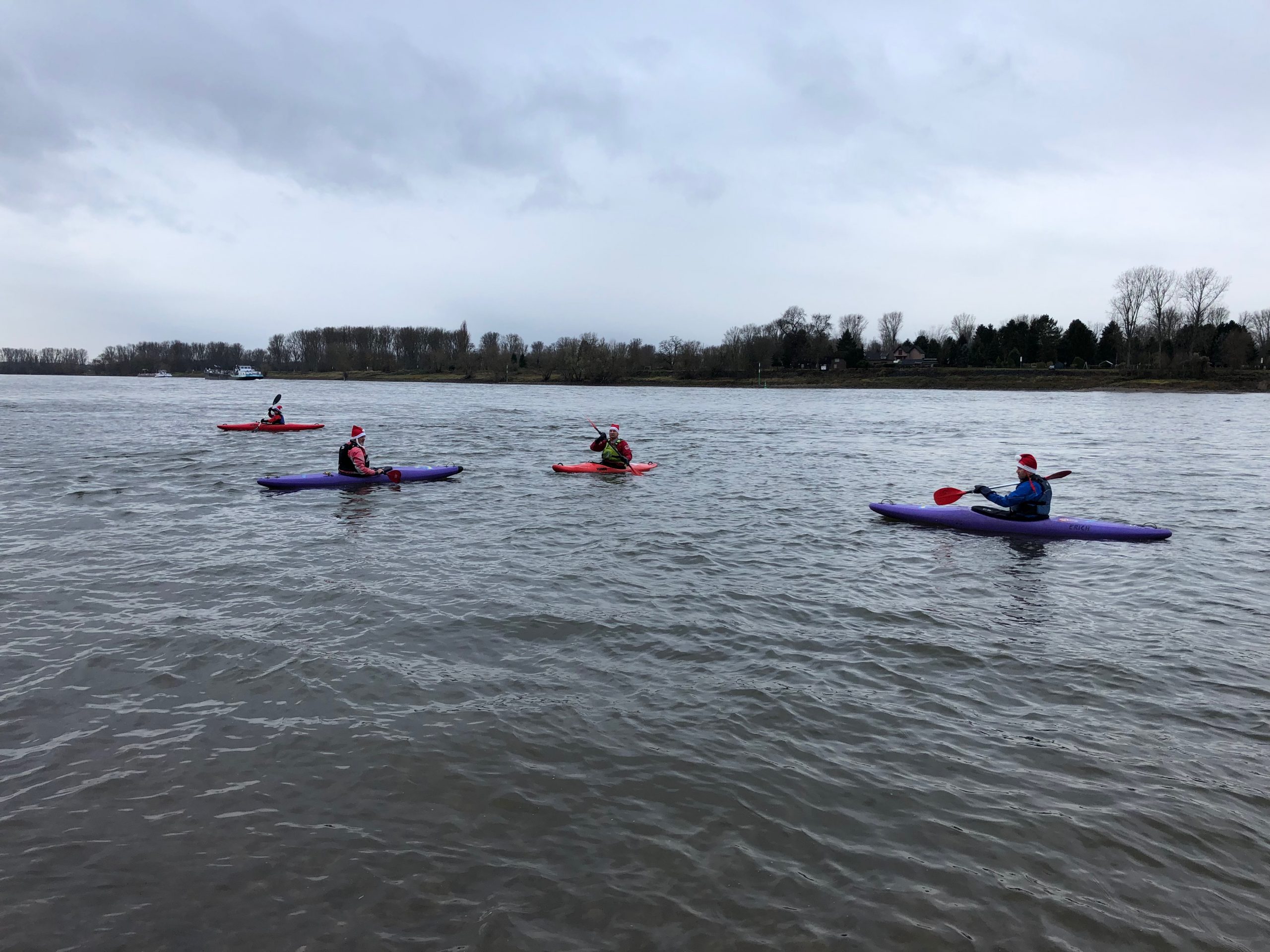 Mehrere Kanufahrer mit Nikolausmützen auf dem Rhein